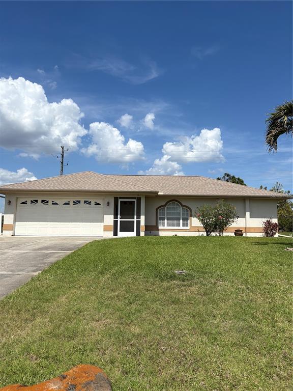 A single-story house with a beige stucco exterior, a two-car garage, and a lawn — 157 ANNAPOLIS LANE, ROTONDA WEST, FL