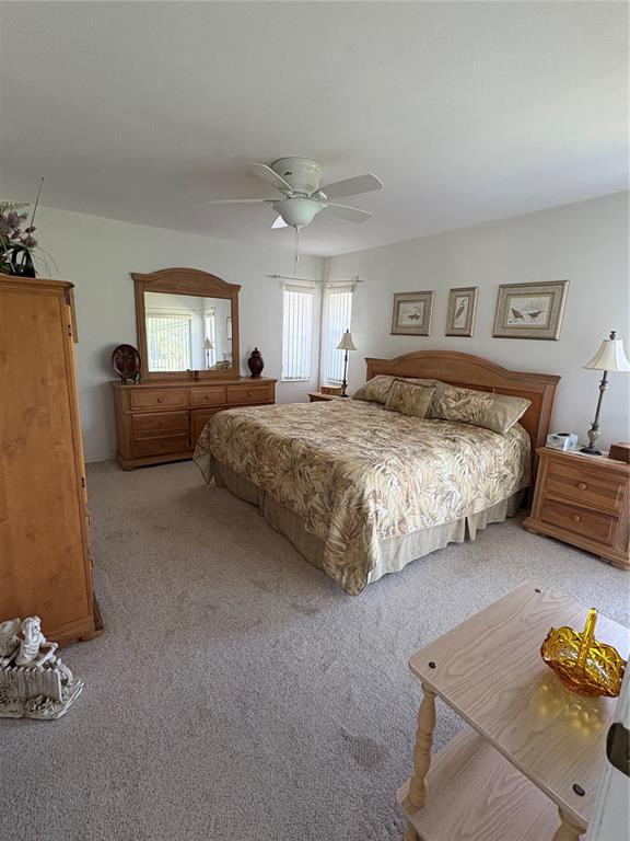 A bedroom features a king-sized bed, wooden furniture, carpeted floors, and a ceiling fan — 157 ANNAPOLIS LANE, ROTONDA WEST, FL