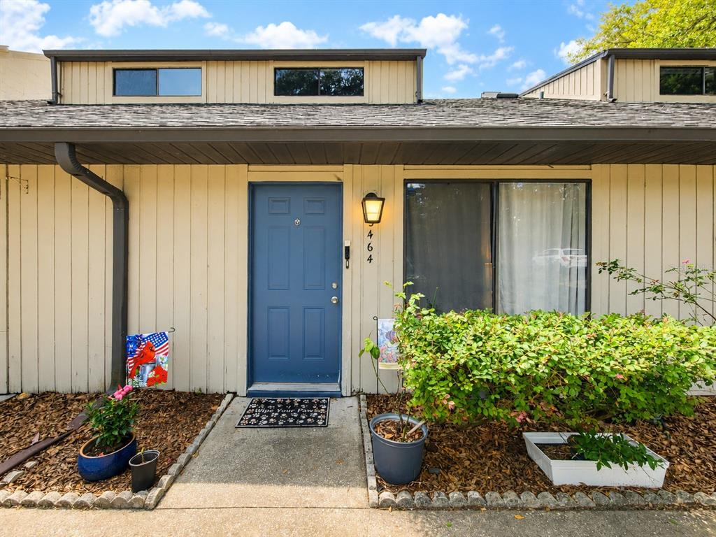 The exterior of a single-story home features a blue front door and a large window — 3464 NW 37TH AVENUE, GAINESVILLE, FL