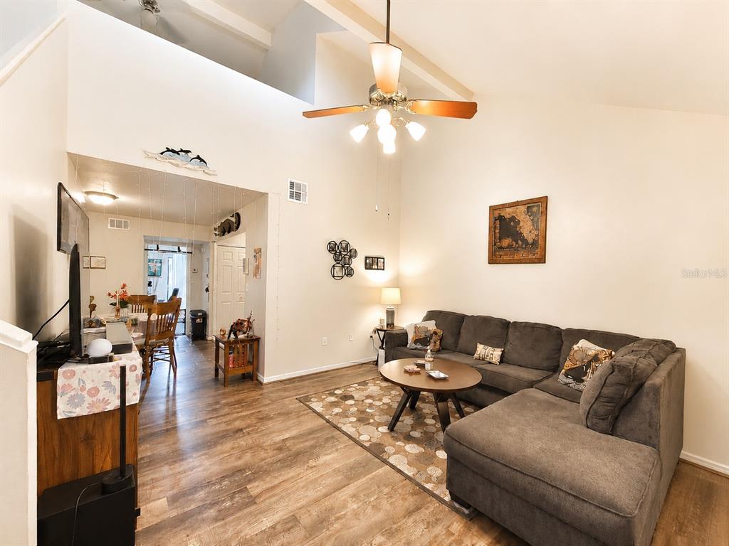 A living room with wood-look flooring, a sectional sofa, and a high vaulted ceiling — 3464 NW 37TH AVENUE, GAINESVILLE, FL