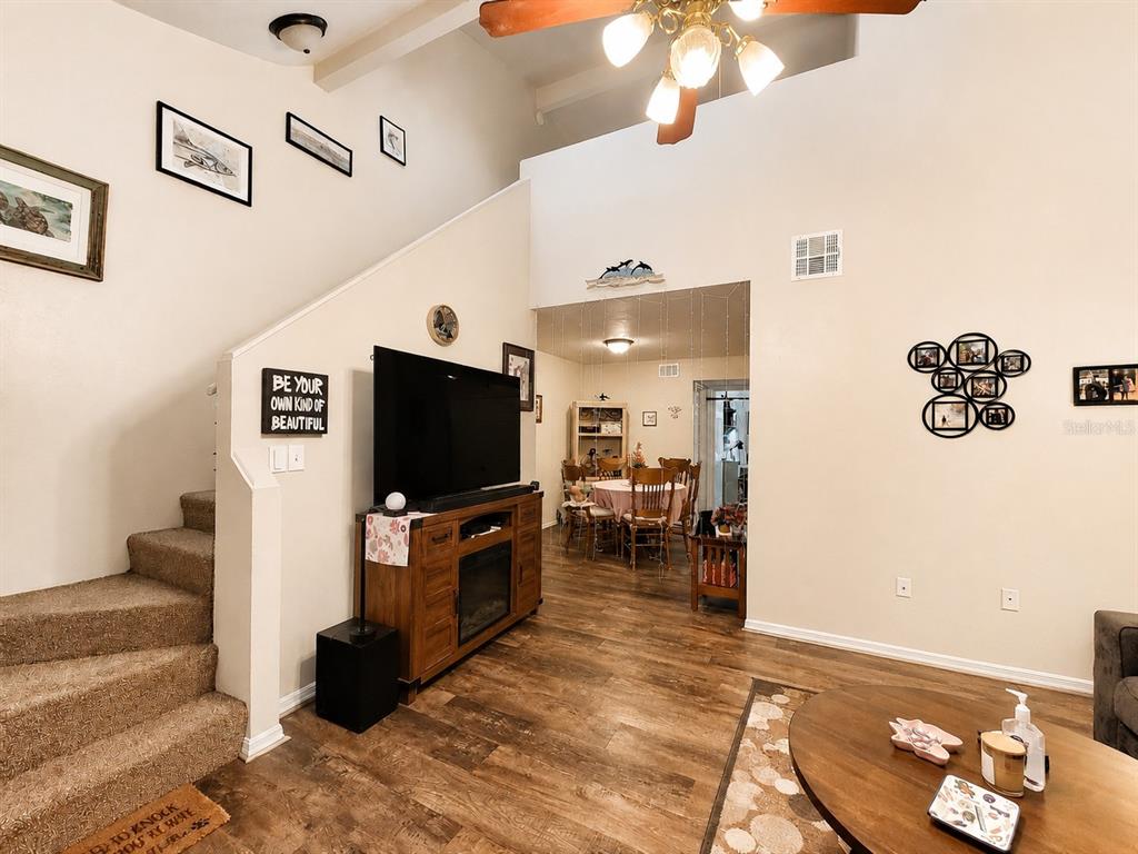 A living room with wood-look flooring, a staircase, a television console, and an adjacent dining area — 3464 NW 37TH AVENUE, GAINESVILLE, FL