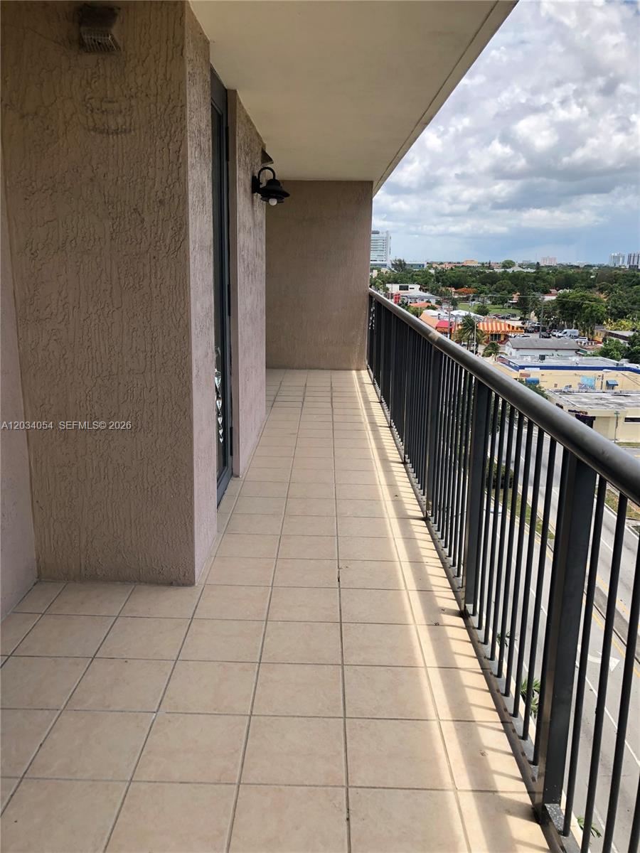 A long, tiled balcony features a black metal railing overlooking a street and city buildings — 1690 SW 27th Ave # 803, Miami FL 33145, MIAMI, FL