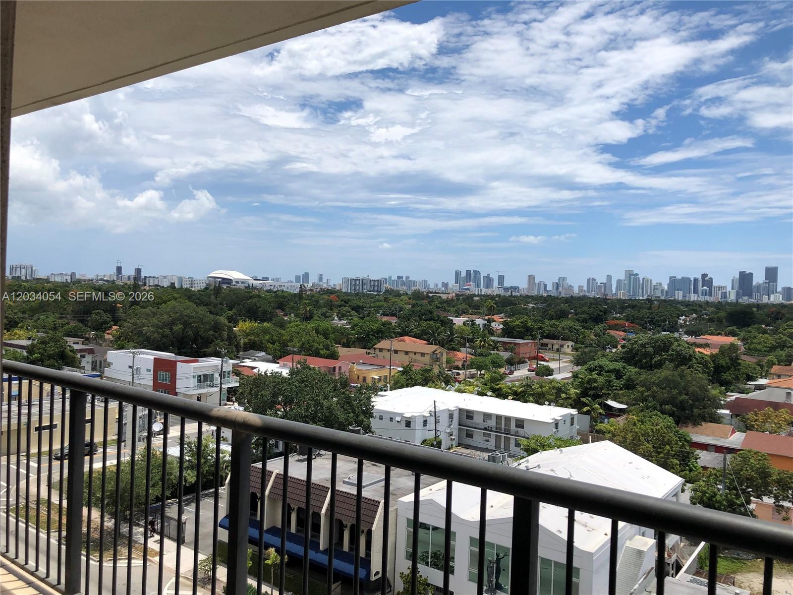 A high-angle view from a balcony overlooks a residential neighborhood and a distant city skyline — 1690 SW 27th Ave # 803, Miami FL 33145, MIAMI, FL
