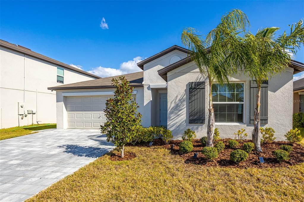 A single-story house with a paved driveway, a two-car garage, and a palm tree — 15415 MILLER CREEK DRIVE, SUN CITY CENTER, FL