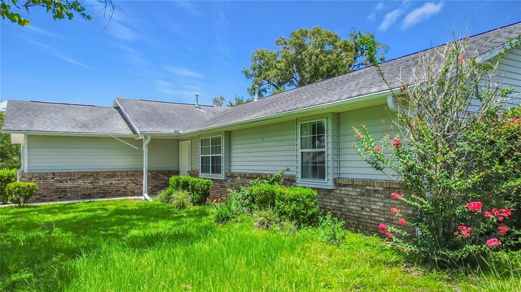A single-story house with light-colored siding, a brick base, and a gray shingled roof — 707 NE 46TH COURT, OCALA, FL