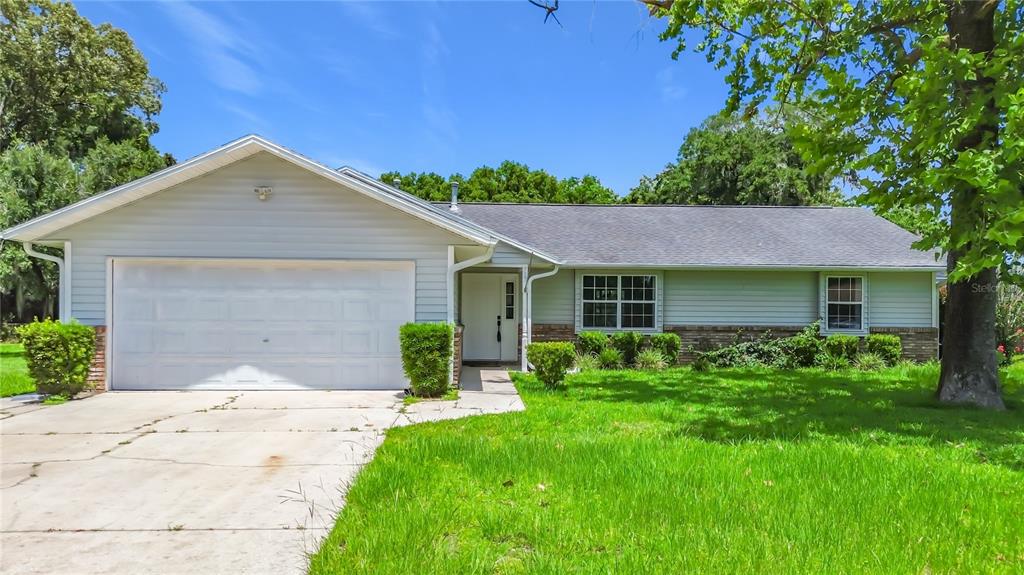 A single-story house with light blue siding, a brick base, and a two-car garage — 707 NE 46TH COURT, OCALA, FL