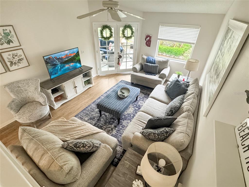 A living room features a sofa, patterned armchair, television console, and a blue area rug — 1350 SIESTA BAYSIDE DRIVE UNIT 1350-B, SARASOTA, FL