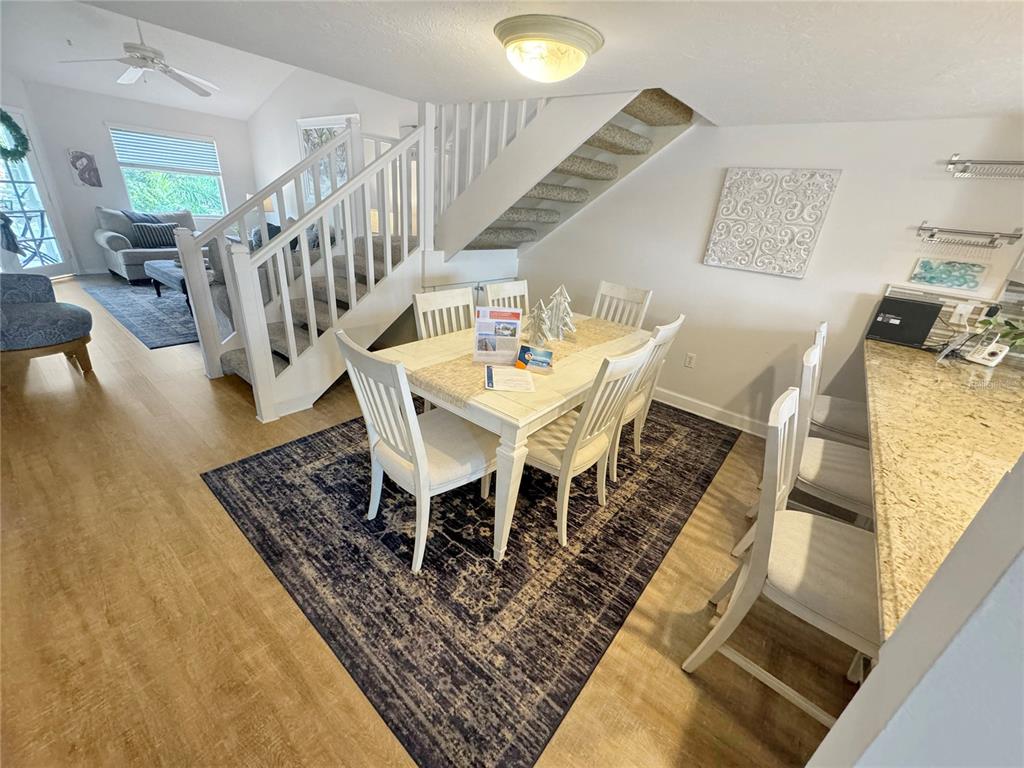A dining area with a white table and chairs sits beside a staircase and kitchen counter — 1350 SIESTA BAYSIDE DRIVE UNIT 1350-B, SARASOTA, FL