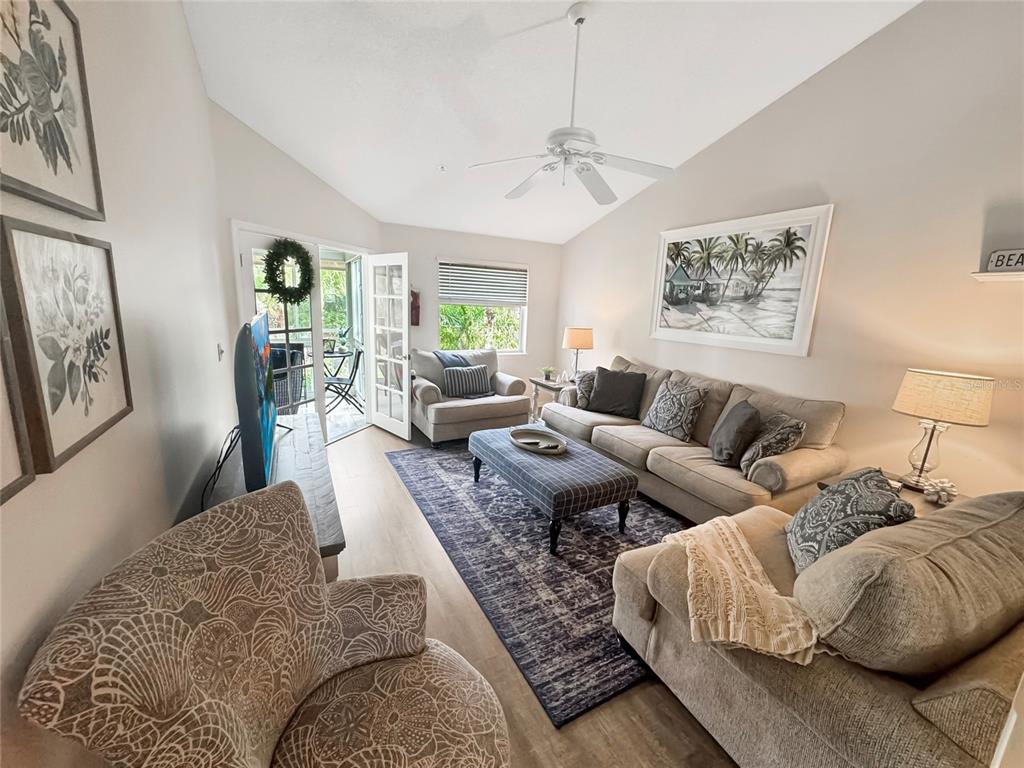 A living room features a vaulted ceiling, a ceiling fan, a sofa, and a patio door — 1350 SIESTA BAYSIDE DRIVE UNIT 1350-B, SARASOTA, FL