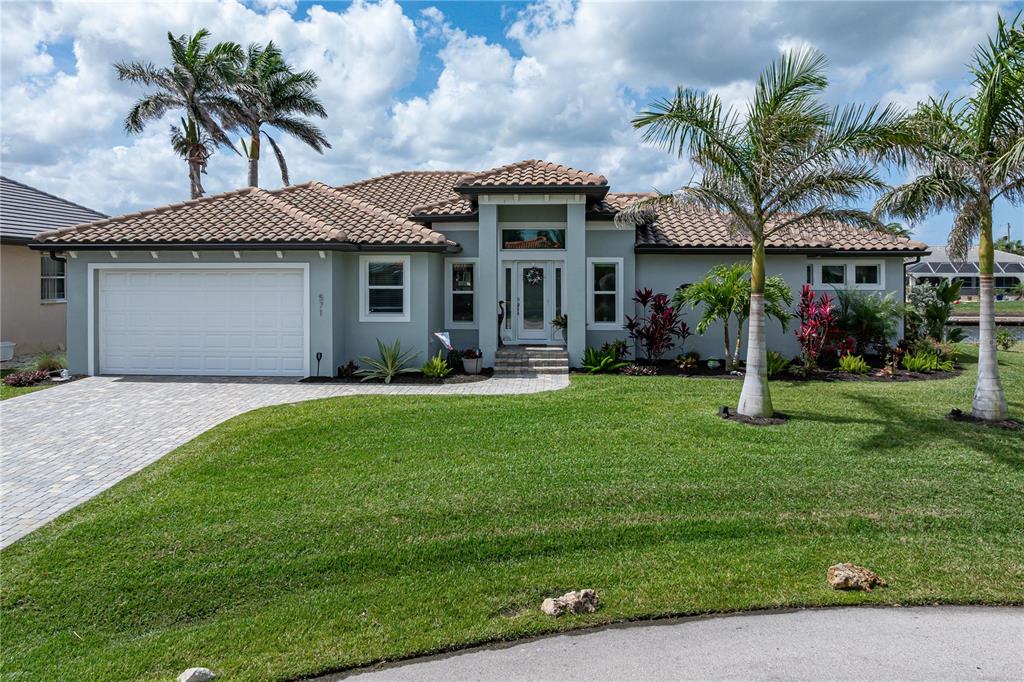 A single-story house with a tiled roof, white garage, and palm trees in the front yard — 571 PORT BENDRES DRIVE, PUNTA GORDA, FL