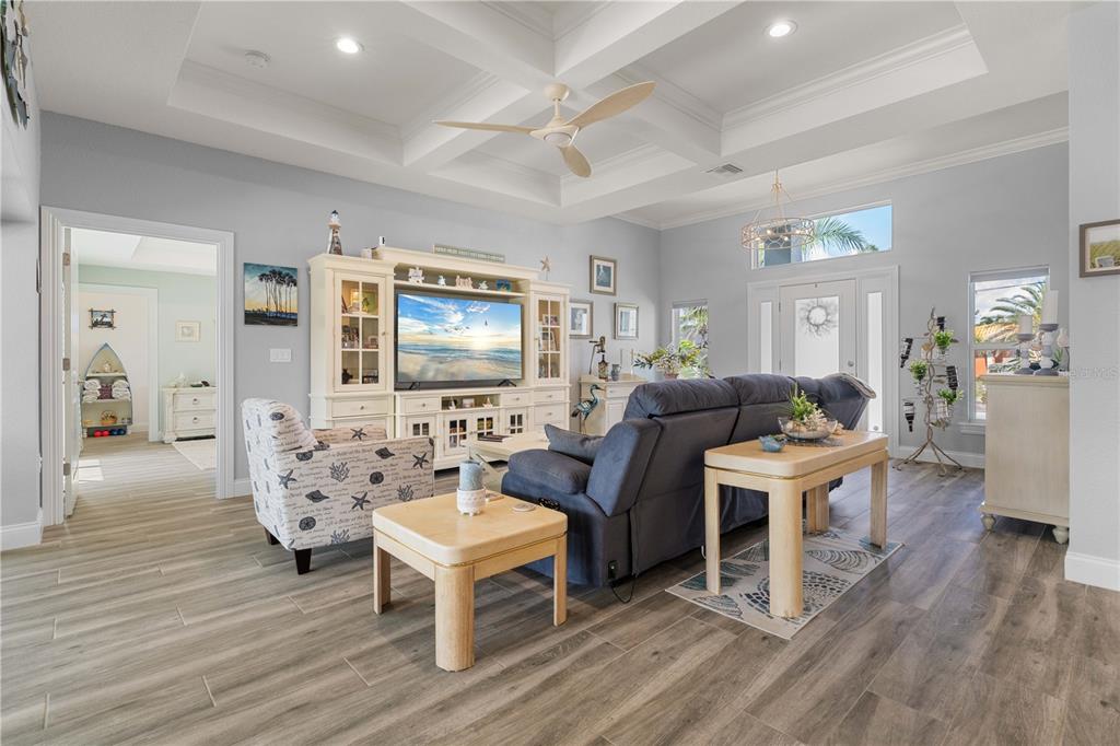 A living room with a coffered ceiling, light wood flooring, and a large entertainment center — 571 PORT BENDRES DRIVE, PUNTA GORDA, FL