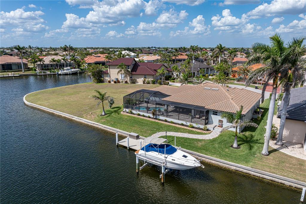 An aerial view of a waterfront house with a pool cage and a boat lift — 571 PORT BENDRES DRIVE, PUNTA GORDA, FL