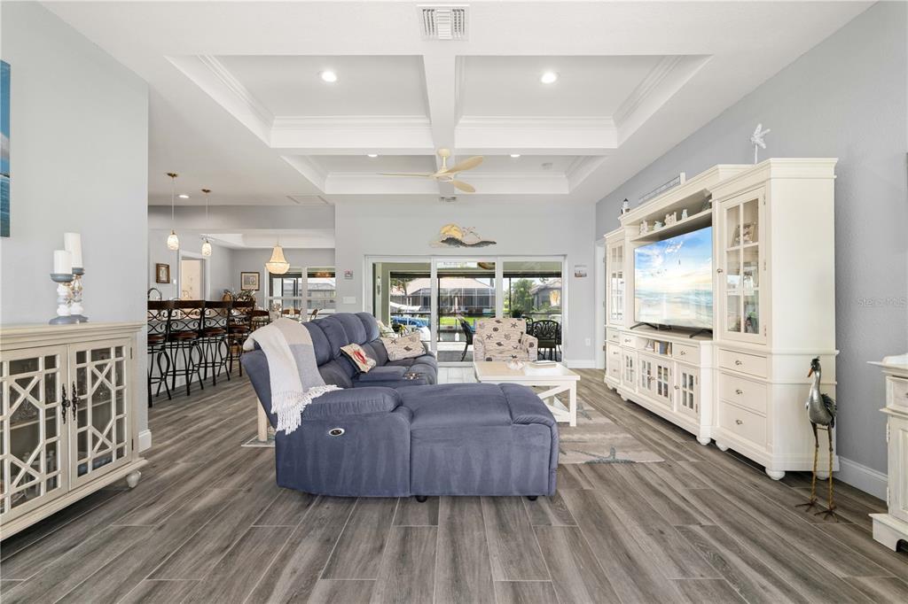 A living room features a blue sectional sofa, white entertainment center, and wood-look tile flooring — 571 PORT BENDRES DRIVE, PUNTA GORDA, FL