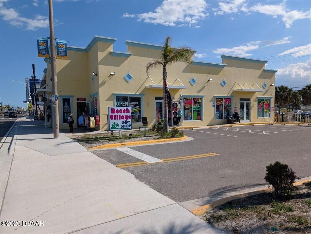 A yellow commercial building with a gift shop sign stands next to a parking lot — 128 S ATLANTIC AVENUE, DAYTONA BEACH, FL