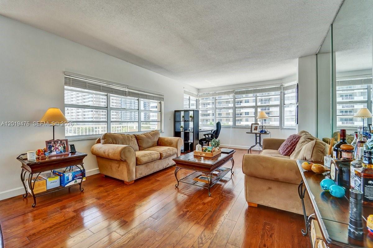 A living room features two tan sofas, a coffee table, and large windows with city views — 1965 S Ocean Dr # 4G, Hallandale Beach FL 33009, HALLANDALE BEACH, FL