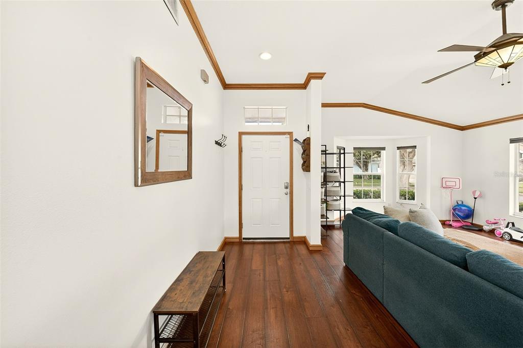 A living room with wood flooring, a blue sofa, and an entryway with a front door — 2927 HICKORY GROVE DRIVE, VALRICO, FL