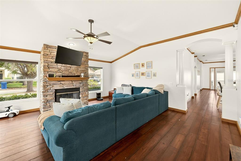 A living room features a stone fireplace, a blue sectional sofa, and dark wood flooring — 2927 HICKORY GROVE DRIVE, VALRICO, FL