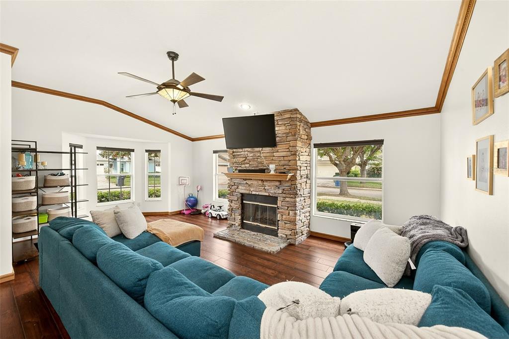 A living room features a stone fireplace, a blue sectional sofa, and hardwood flooring — 2927 HICKORY GROVE DRIVE, VALRICO, FL