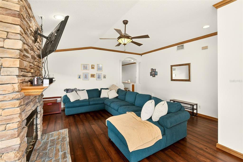 A living room features a stone fireplace, a large blue sectional sofa, and hardwood floors — 2927 HICKORY GROVE DRIVE, VALRICO, FL
