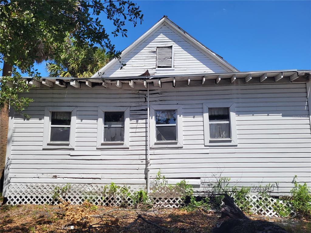 The exterior of a weathered, white wood-sided house with a lattice foundation and four windows — 2902 N ALBANY AVENUE, TAMPA, FL