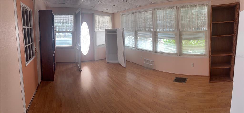 A room with wood-look flooring, a white door, a chest freezer, and built-in shelving — 3301 ALT 19 UNIT 130, DUNEDIN, FL