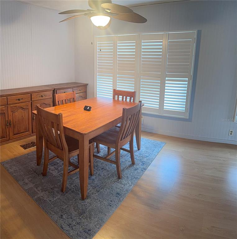 A dining room features a wooden table and chairs on a rug under a ceiling fan — 3301 ALT 19 UNIT 130, DUNEDIN, FL