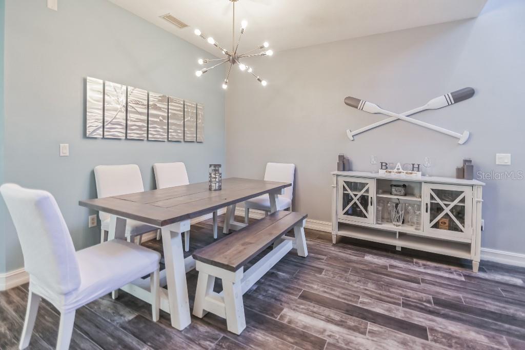 A dining room features a wooden table, white chairs, a bench, and a sideboard — 1340 RIBOLLA DRIVE, PALM HARBOR, FL