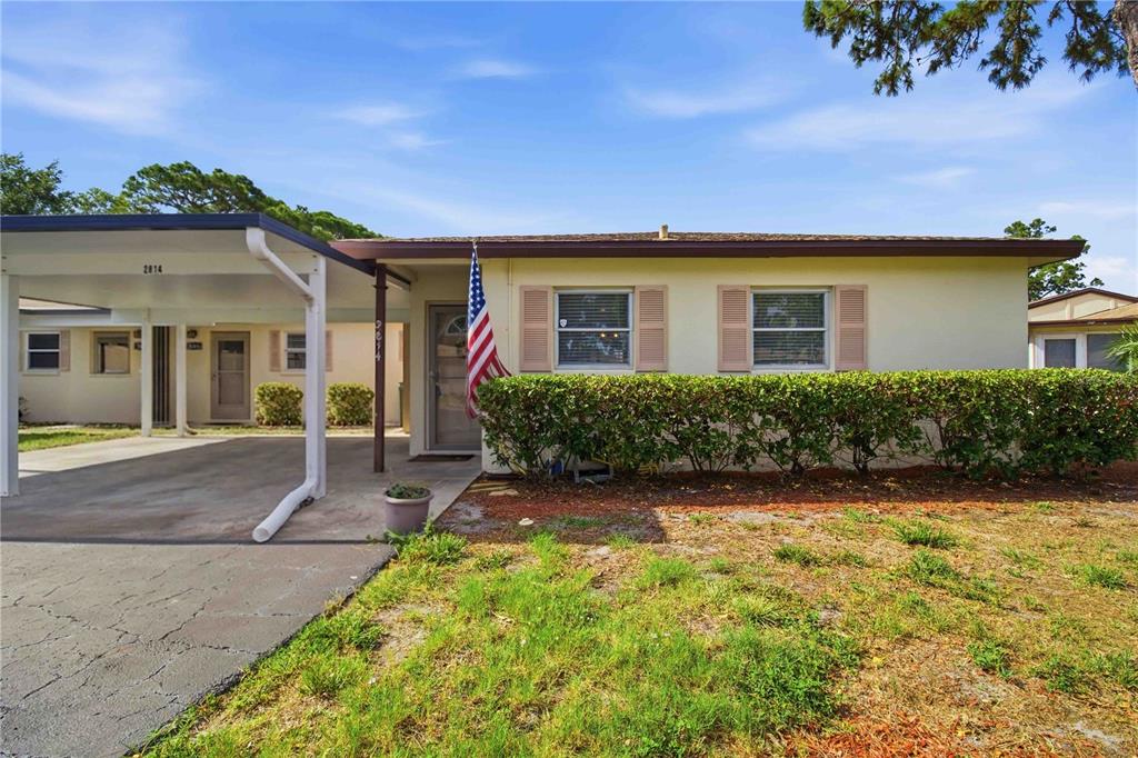A single-story house features a carport, a front hedge, and an American flag — 2814 SWIFTON DRIVE UNIT 108, SARASOTA, FL