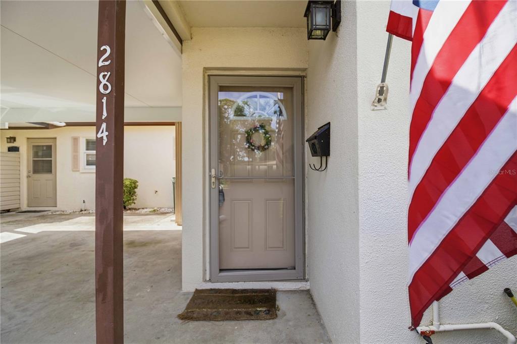 A front entrance features a storm door, a welcome mat, and an American flag — 2814 SWIFTON DRIVE UNIT 108, SARASOTA, FL