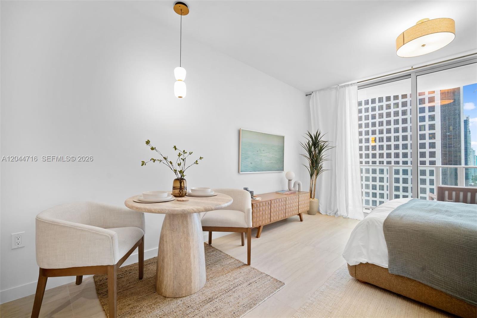 A bedroom features a small dining table, a wooden media console, and a balcony view — 77 SE 5 Street # 2313, Miami FL 33131, MIAMI, FL