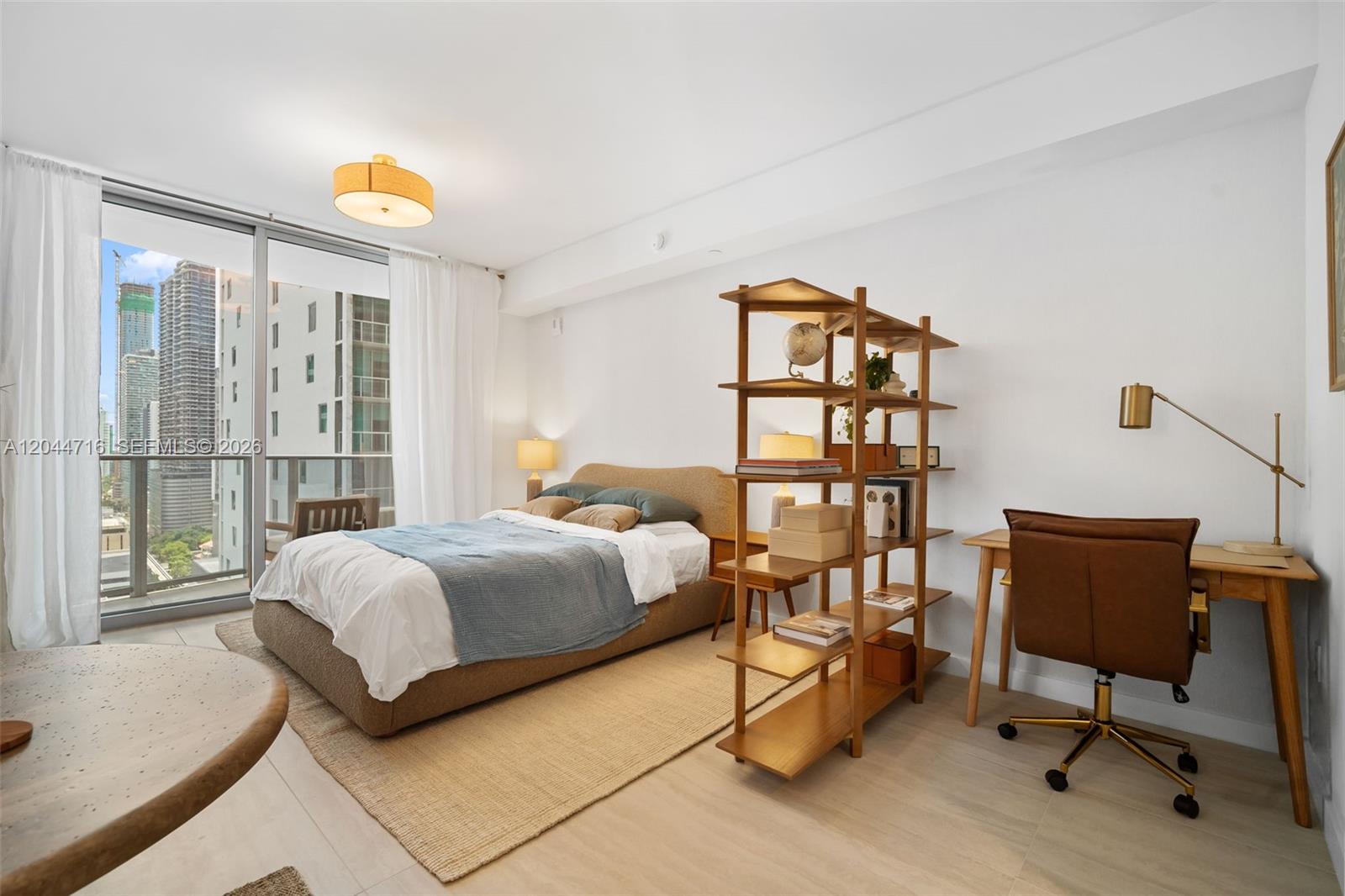 A bedroom features a bed, a wooden bookshelf, a desk, and a balcony with city views — 77 SE 5 Street # 2313, Miami FL 33131, MIAMI, FL