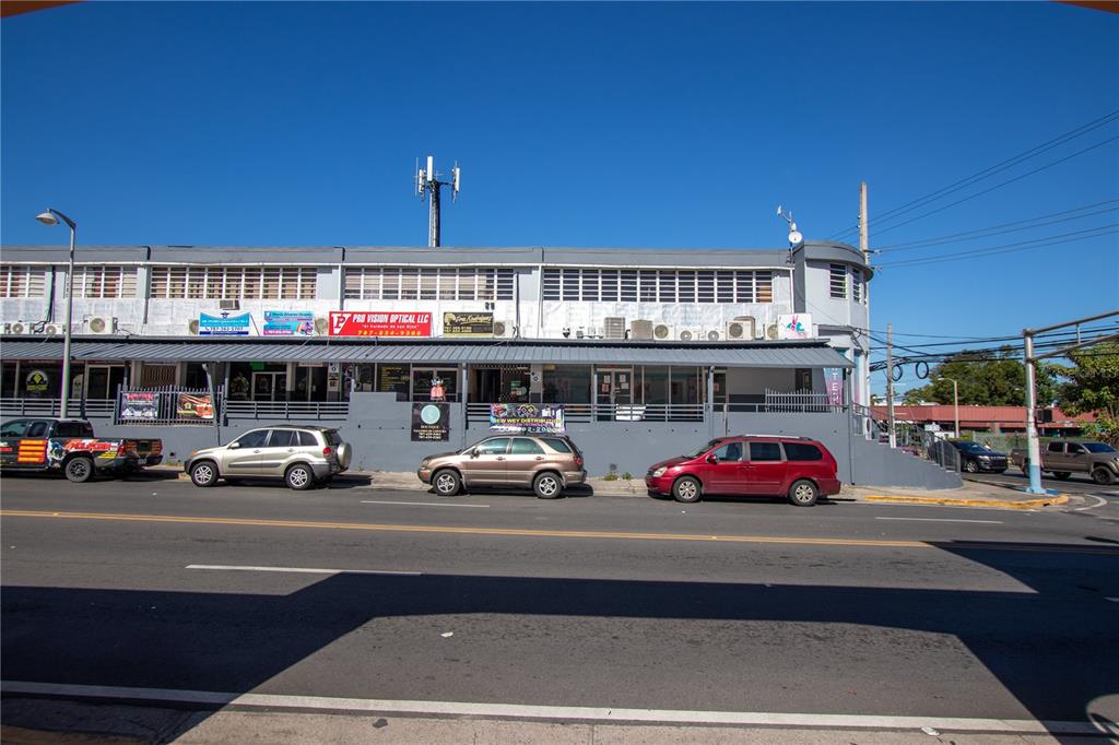 A two-story commercial building with multiple storefronts and parked cars along a street — Ave Castro Perez, SAN GERMAN, SAN GERMAN, PR
