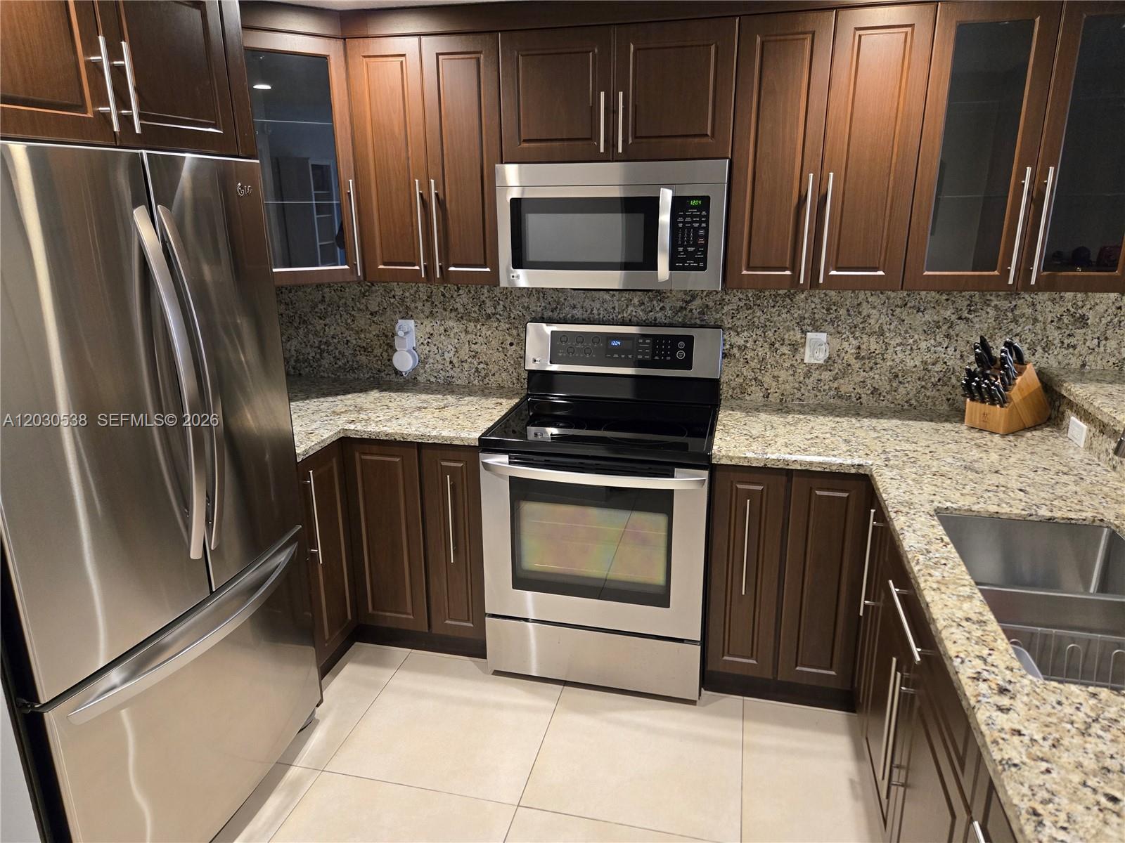 A kitchen features dark wood cabinets, stainless steel appliances, and speckled granite countertops — 11213 SW 88 ST # 110B, Miami FL 33176, MIAMI, FL