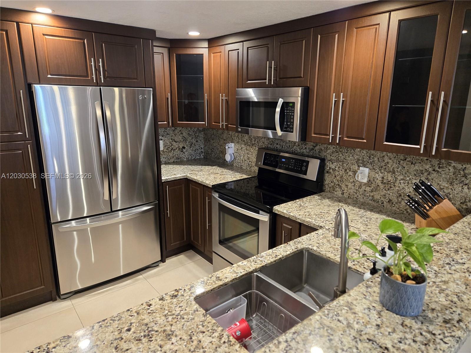 A kitchen features dark wood cabinets, stainless steel appliances, and speckled granite countertops — 11213 SW 88 ST # 110B, Miami FL 33176, MIAMI, FL