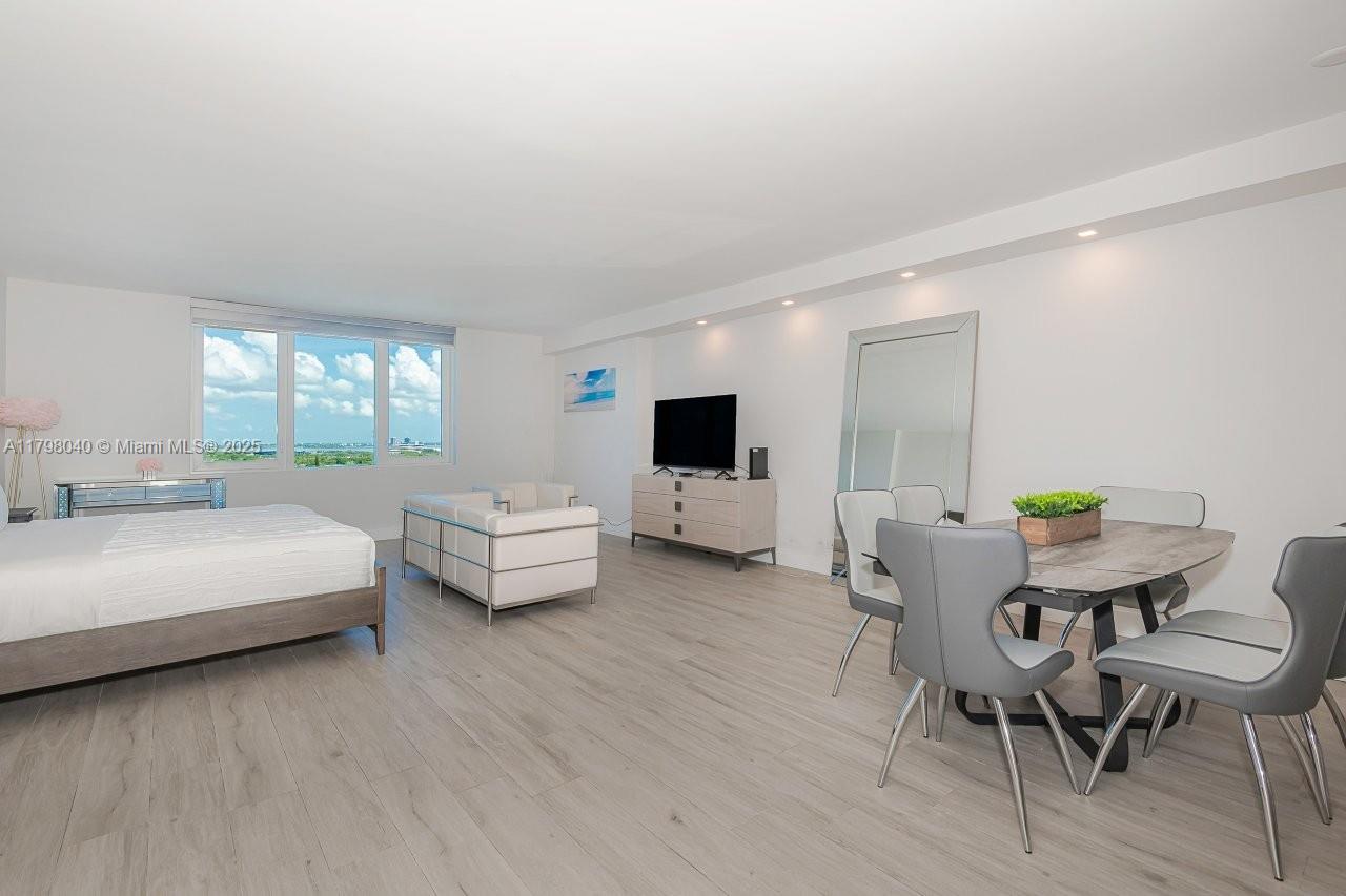 A spacious bedroom features light wood flooring, a dining area, and large windows with views — 2301 Collins Ave # 1531, Miami Beach FL 33139, MIAMI BEACH, FL