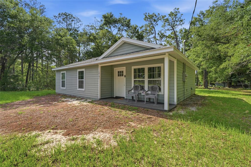 A light green single-story house with a covered front porch sits on a grassy lot — 10191 NE 67TH LANE, BRONSON, FL