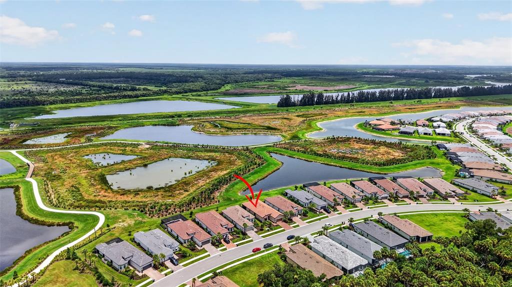 An aerial view shows a suburban neighborhood with houses bordering several ponds and wetlands — 10132 SILENT NIGHT LANE, SARASOTA, FL