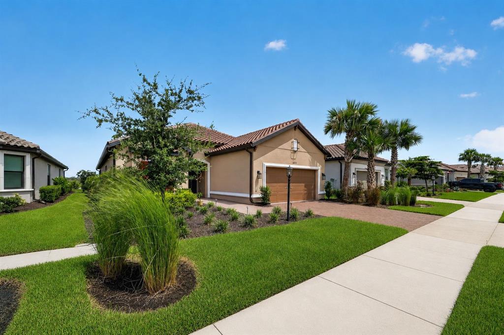 A single-story house with a tan stucco exterior, tile roof, and a paved driveway — 10132 SILENT NIGHT LANE, SARASOTA, FL