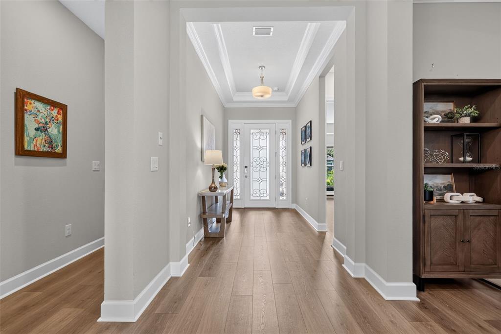 A bright entryway features light wood flooring, a tray ceiling, and a glass-paneled front door — 10132 SILENT NIGHT LANE, SARASOTA, FL