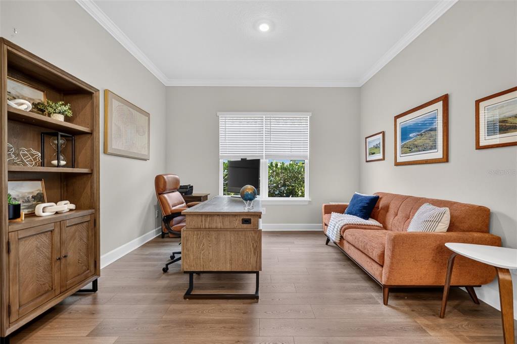 A home office features a wooden desk, a brown sofa, a bookshelf, and wood-look flooring — 10132 SILENT NIGHT LANE, SARASOTA, FL