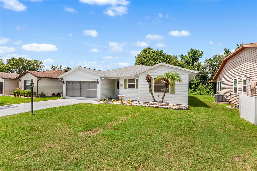 A white single-story house with a screened garage and a small palm tree in front — 4976 PLEASANT HOLLOW TRL, LAKELAND, FL