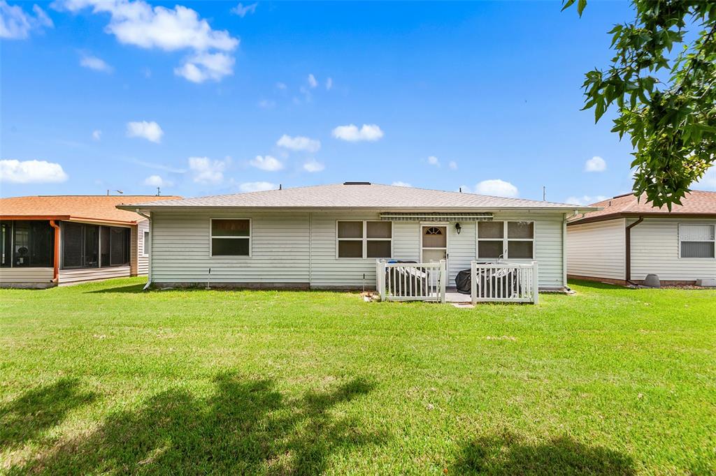 The exterior rear view of a single-story house with light siding and a small patio — 4976 PLEASANT HOLLOW TRL, LAKELAND, FL