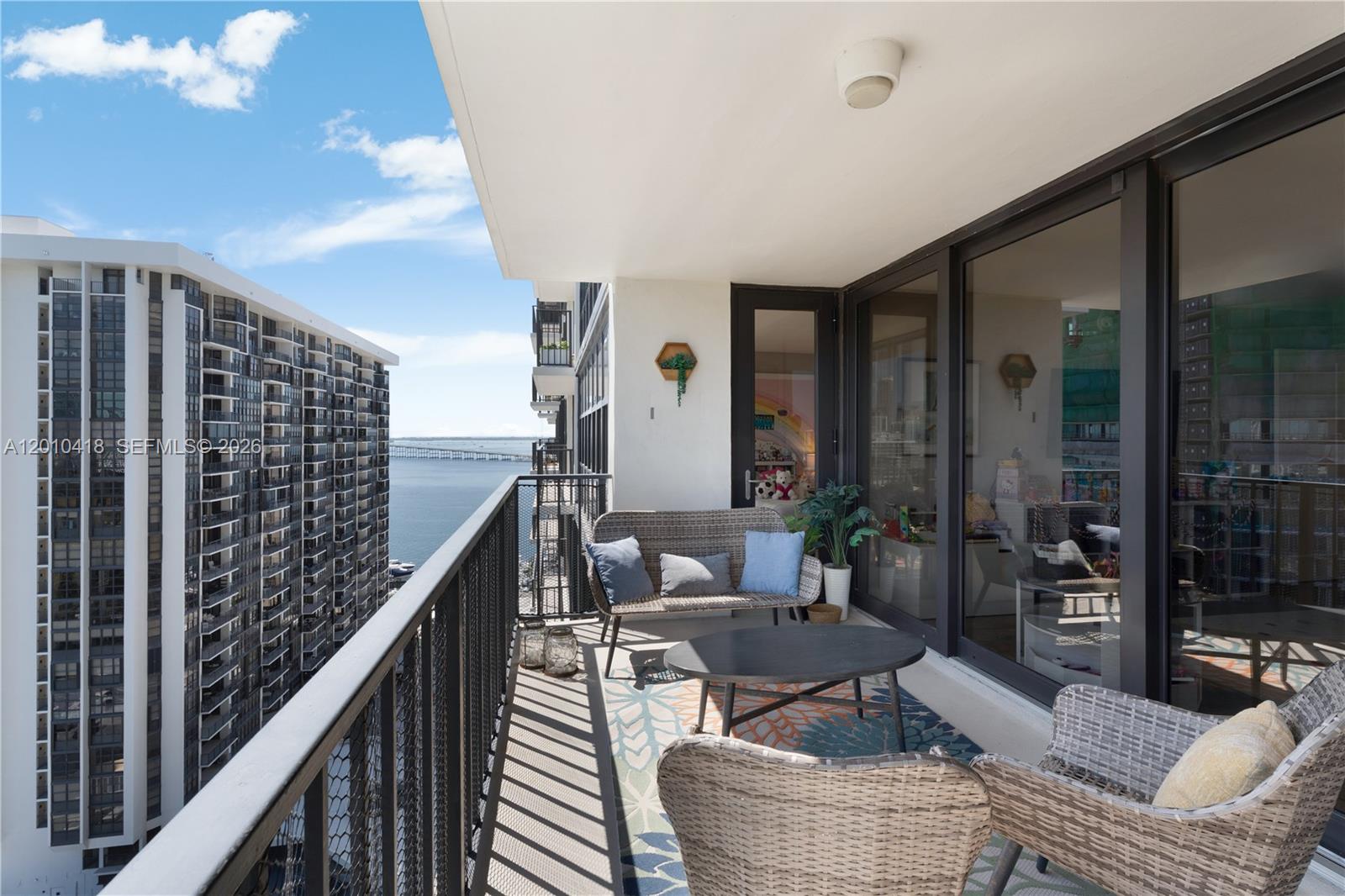 An open-concept living and dining area features light wood floors, white walls, and modern furniture — 1901 Brickell Ave # B1809, Miami FL 33129, MIAMI, FL