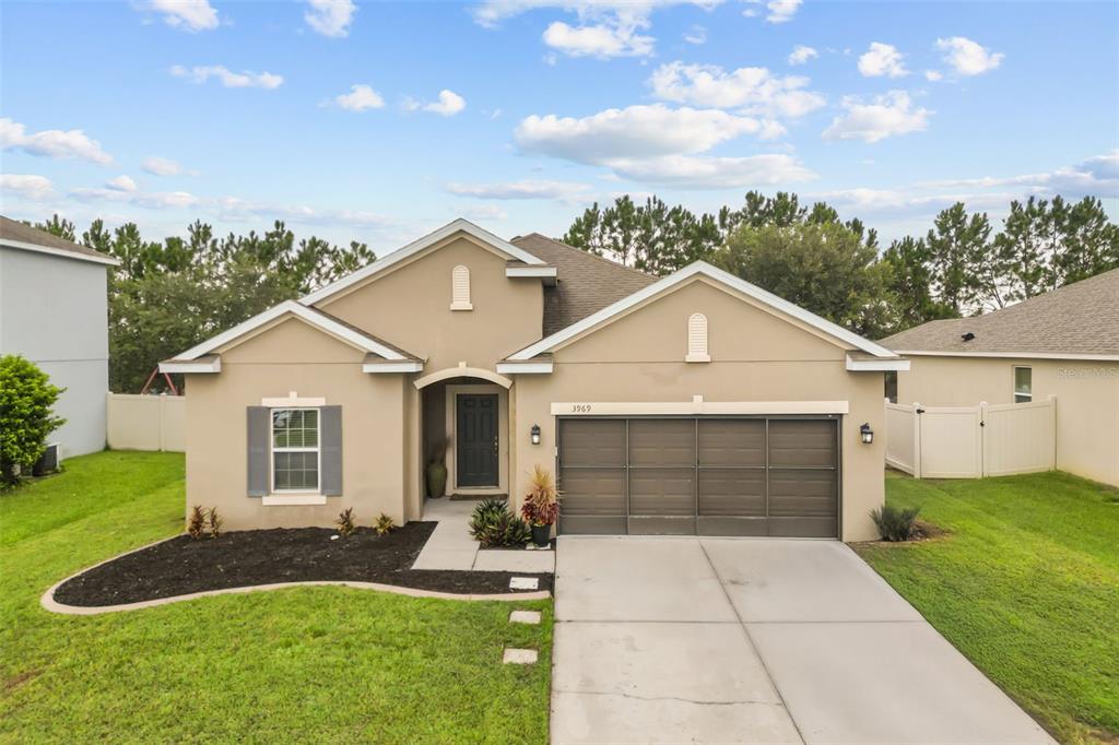 A single-story tan house with a two-car garage and a front walkway — 3969 ETERNITY CIRCLE, ST CLOUD, FL