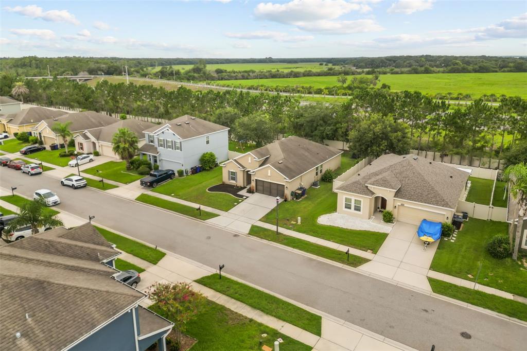 An aerial view shows a suburban street with single-family homes and a large green field — 3969 ETERNITY CIRCLE, ST CLOUD, FL