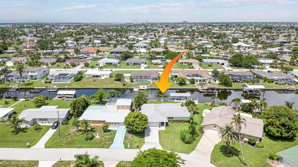 An aerial view shows a residential neighborhood with houses along a canal and boat docks — 5204 TOWER DRIVE, CAPE CORAL, FL