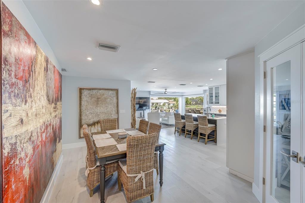 A dining area with wicker chairs leads into an open-concept kitchen and living space — 5204 TOWER DRIVE, CAPE CORAL, FL