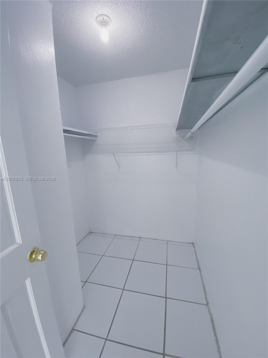 A small walk-in closet features white walls, tile flooring, and wire shelving — 870 NW 87th Ave # 110, Miami FL 33172, MIAMI, FL