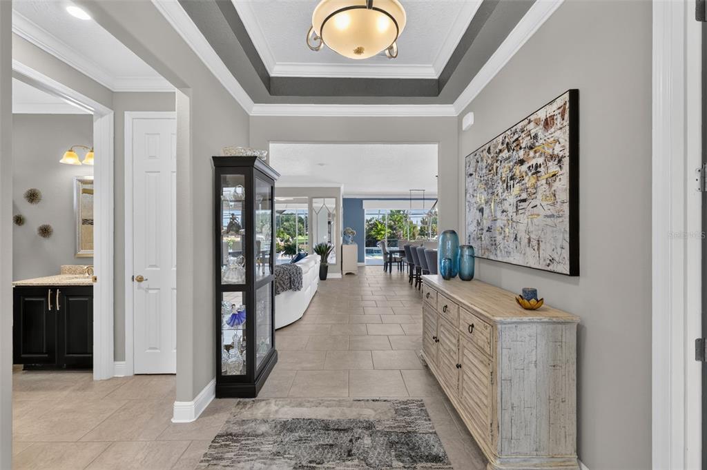 A tiled entryway features a tray ceiling, a display cabinet, and a wooden console table — 9133 SW 82ND LANE, OCALA, FL