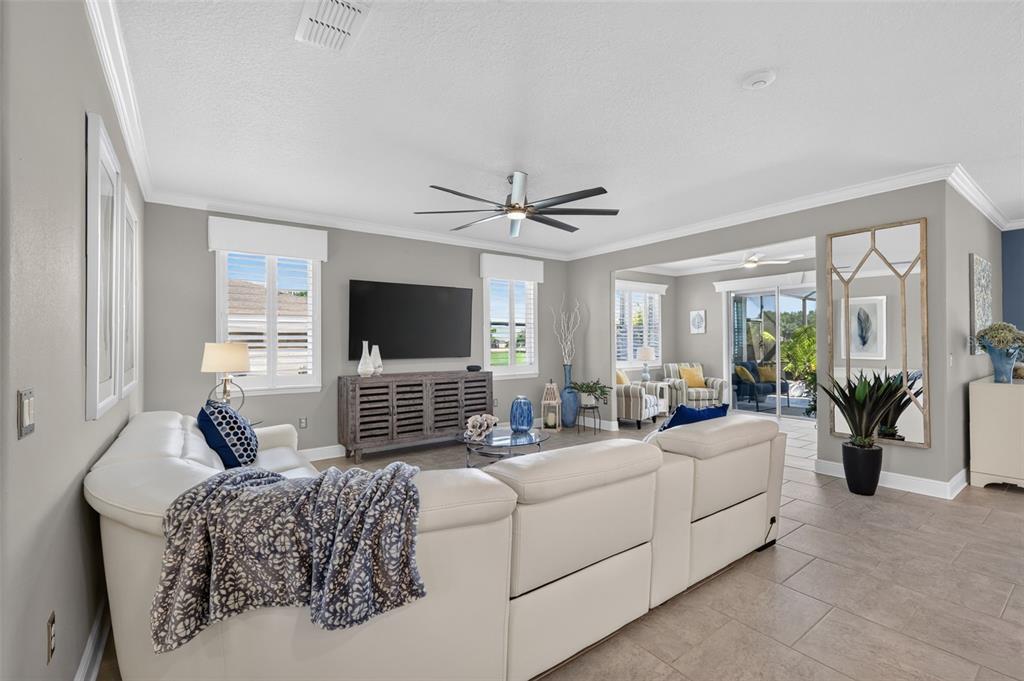 A living room features a white sectional sofa, a television on a console, and tile flooring — 9133 SW 82ND LANE, OCALA, FL